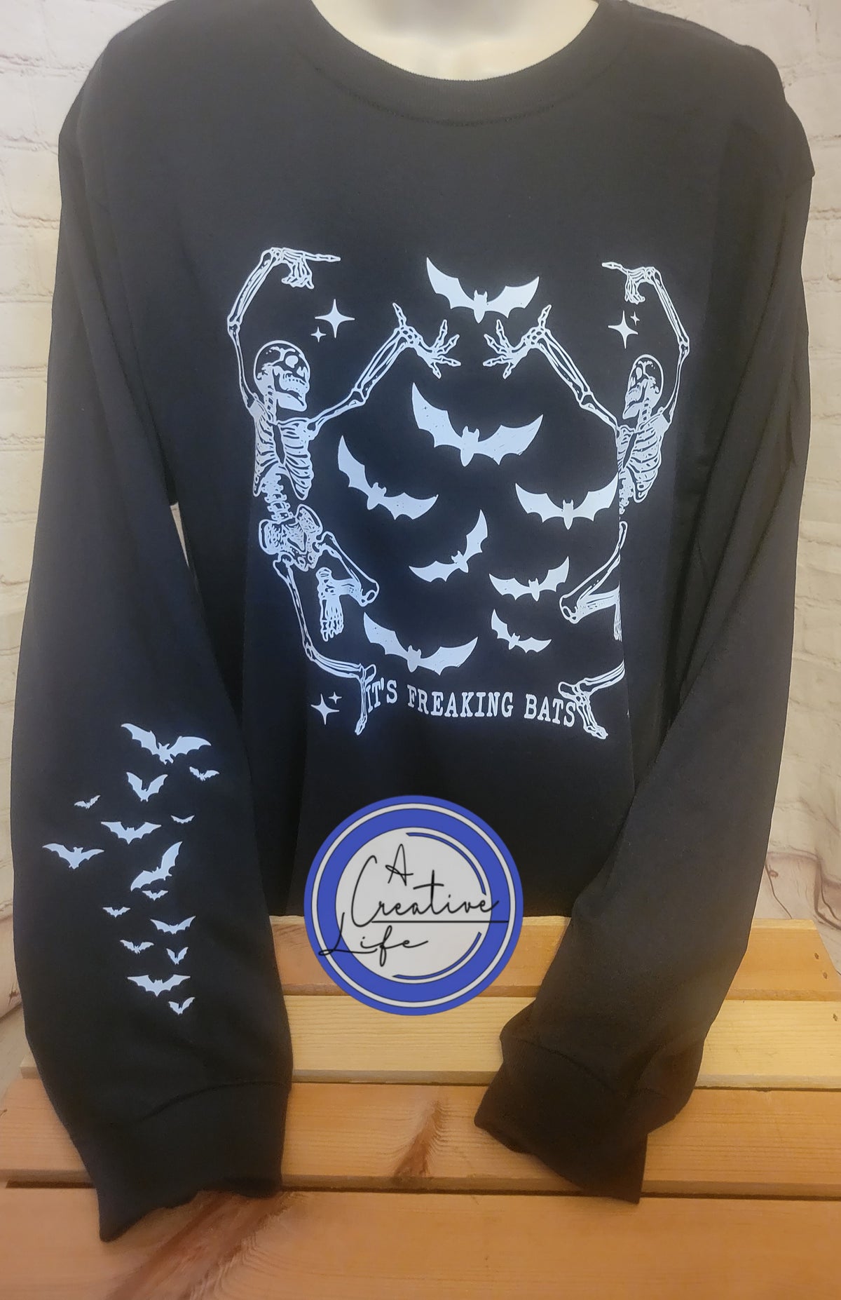 A black long sleeve tee with white graphic prints of bats and skeletons on the front and sleeves.