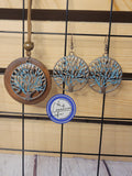 A set of jewelry featuring a wooden necklace with bronze Tree of Life pendants and matching earrings, displayed on a wooden background.