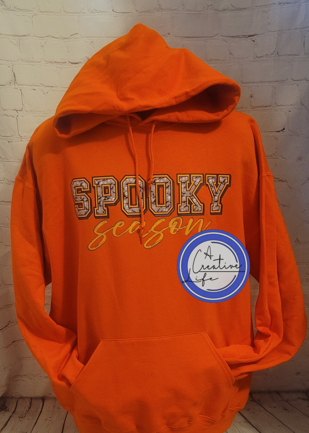 An orange hooded sweatshirt with 'SPOOKY SEASON' text in black on the front.