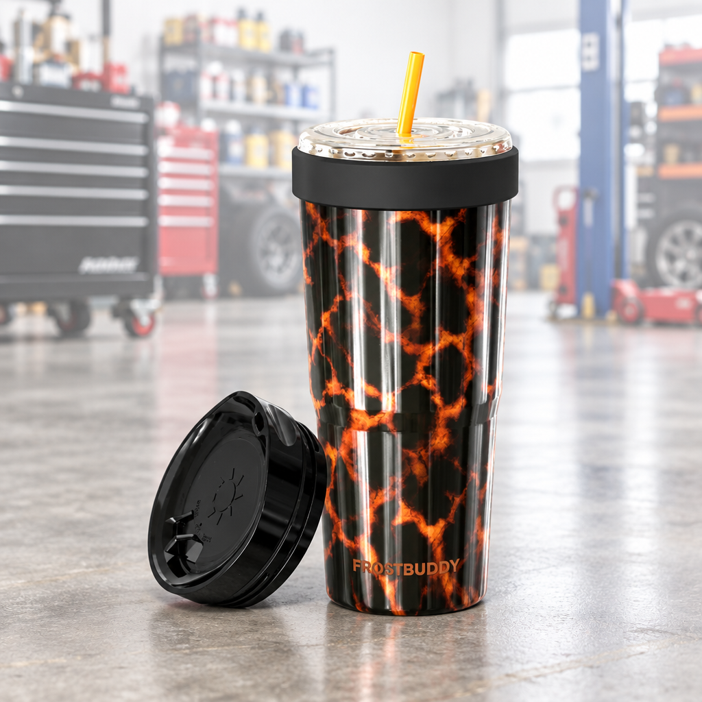 A Frost Buddy insulated travel tumbler with a black and orange lava pattern, shown with its black lid off next to the cup on a white background.