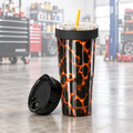 A Frost Buddy insulated travel tumbler with a black and orange lava pattern, shown with its black lid off next to the cup on a white background.