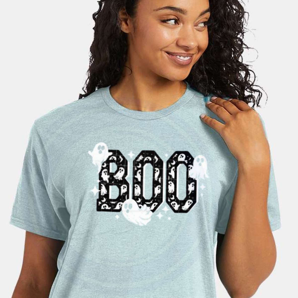 Woman wearing a light blue t-shirt with 'BOO' and ghost graphics on a plain background