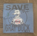 heather blue shirt with graphic of a duck holding a sign and text 'Save the Gray Duck' on a wooden surface.