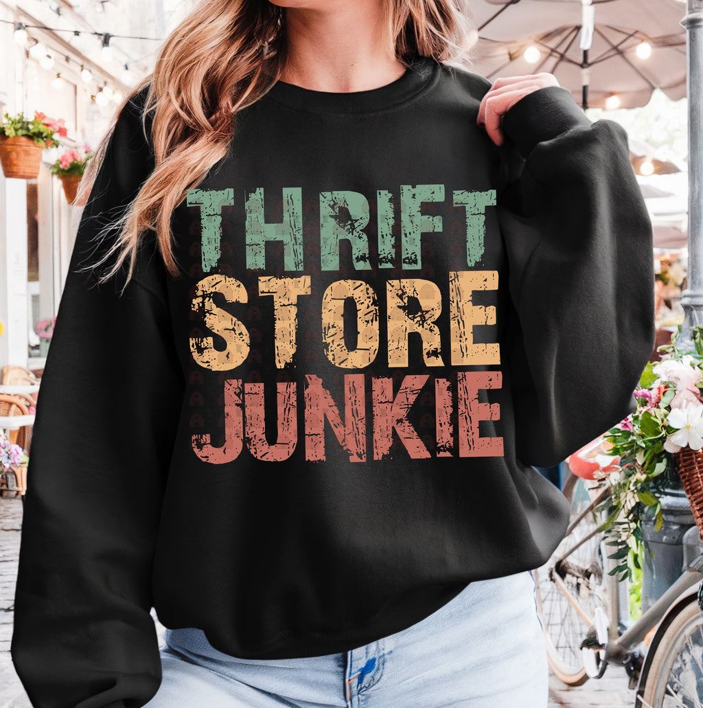 Person wearing a black sweatshirt with 'Thrift Store Junkie' text in colorful letters, standing in an outdoor setting.