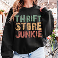 Person wearing a black sweatshirt with 'Thrift Store Junkie' text in colorful letters, standing in an outdoor setting.