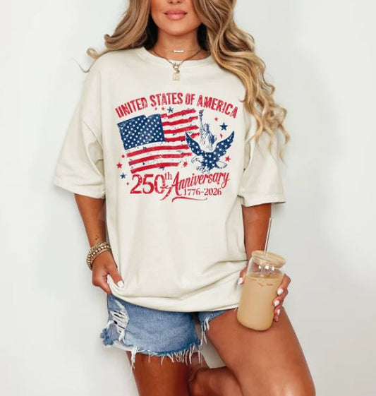 Person wearing a white t-shirt with American flag and eagle design, holding a drink.